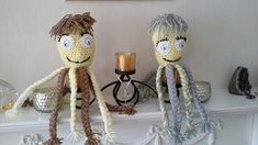 two knitted octopus dolls sitting next to each other on a mantle with a candle