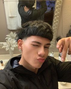 a young man brushing his hair in front of a mirror