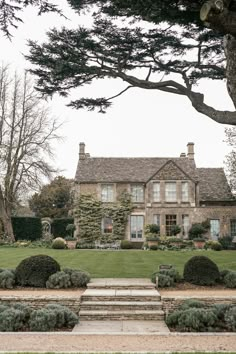 a large house with steps leading up to the front door and trees in the background