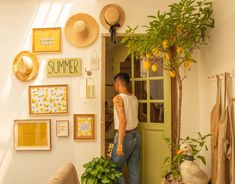 a woman standing in the doorway of a room with lots of pictures on the wall