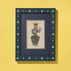 a cross stitch picture hanging on a yellow wall with blue frame and stars around it