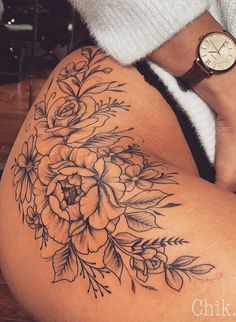 a close up of a person's thigh with flowers on it and a watch