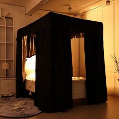 a canopy bed with curtains on it in the middle of a room that has white walls and wooden floors