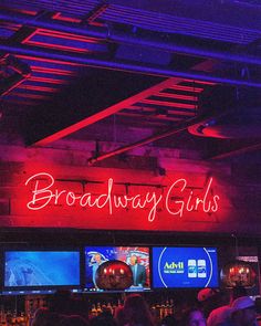 the neon sign for broadway girls is lit up in front of a bar full of people