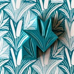 an origami flower on a blue and white wallpaper pattern with green leaves