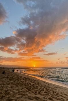 people are walking on the beach at sunset