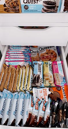 an open refrigerator filled with lots of different types of snacks and desserts on top of it