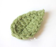 a crocheted green leaf sitting on top of a white table