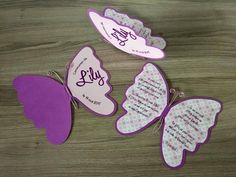 three butterfly shaped magnets with words on them sitting on top of a wooden table