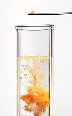 an orange in a glass with water and a straw sticking out of the top, on a white background