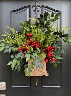 a christmas wreath on the front door of a house with holly and berries hanging from it