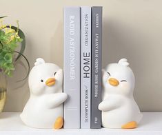 two white bookends sitting on top of a shelf next to a potted plant