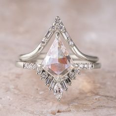 a white gold ring with a pear shaped cut diamond surrounded by smaller round and baguette diamonds