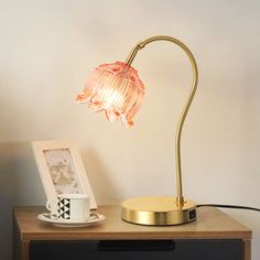 a table lamp on top of a dresser next to a coffee cup and photo frame