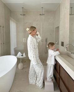 a woman and child standing in front of a bathroom sink