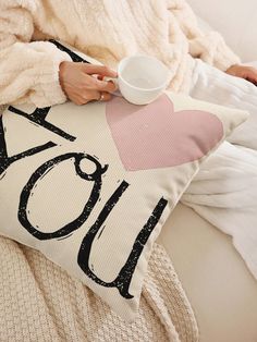 a woman sitting on a couch holding a pillow with the word love written on it