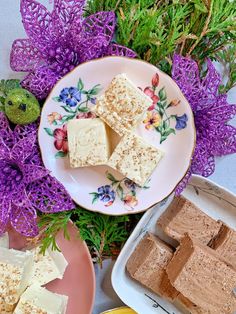 there are many different desserts on the plates and in front of them is purple flowers