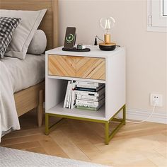 a nightstand with books and an alarm clock on it next to a bed in a bedroom