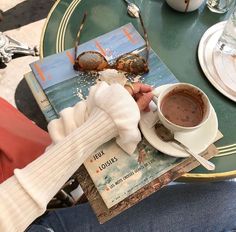 a person sitting at a table with a book and cup of coffee