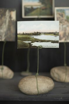 there are some pictures on the table with rocks in front of them and one is holding a piece of art