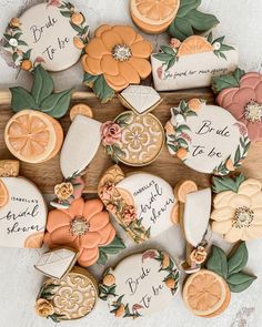 cookies decorated with oranges and flowers on top of a wooden board that says bride to be