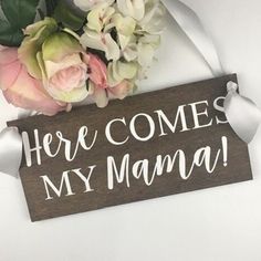 there is a wooden sign that says here comes my mama with flowers on the table