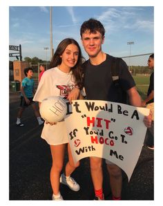 two people standing next to each other holding a sign that says it would be a hit if you go with me