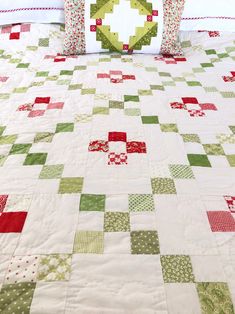 a quilted bedspread with red, green and white squares on the edges