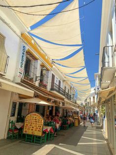 people are sitting at tables under the awnings in an alleyway between buildings