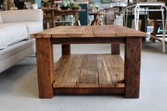 a coffee table made out of wooden planks in a room with couches and tables