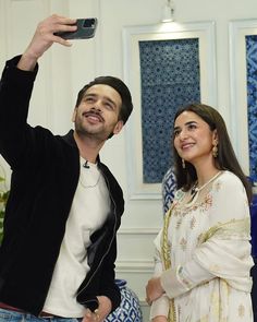 a man taking a selfie with a woman standing next to him and holding a cell phone up in the air