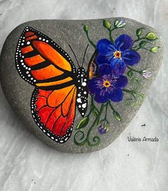 a painted rock with flowers and a butterfly on it