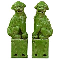 two green foo foo statues sitting next to each other on top of a white background