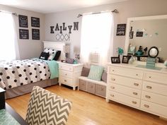 a bedroom decorated in black and white with polka dots on the bed, chevron chair, dressers, and mirror