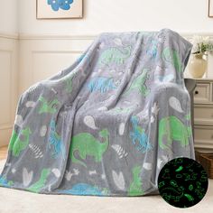 a child's blanket with dinosaurs on it and a green glow in the middle