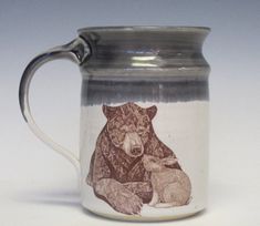 a ceramic mug with a bear and cub on the inside is sitting in front of a white background