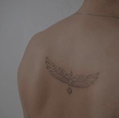 the back of a woman's shoulder with a bird tattoo on her left arm