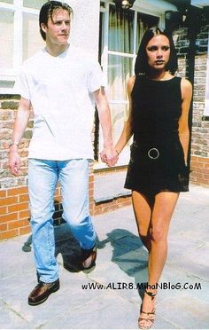 a man and woman holding hands walking down the sidewalk