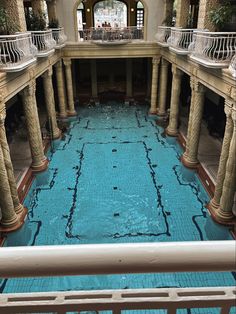 an indoor swimming pool surrounded by stone pillars and columns with balconies on each side