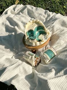 a cake sitting on top of a white blanket next to a wooden bowl filled with frosting