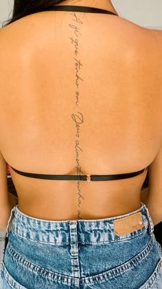 the back of a woman's body with writing on it and an arrow tattoo