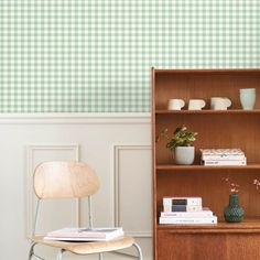 a wooden chair sitting next to a bookshelf filled with books and vases