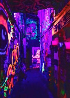 an alleyway with graffiti painted on the walls and floor, along with neon lights