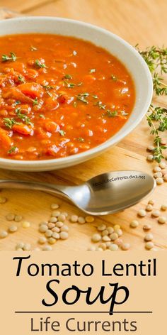 tomato lentil soup in a white bowl on a wooden table with a spoon next to it