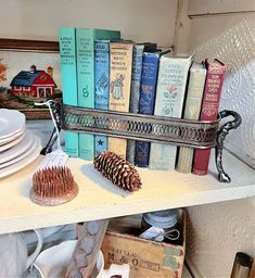 a shelf filled with books next to a pine cone on top of a white plate