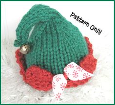 a green knitted hat with red and white trimmings on the bottom, sitting on top of a pile of fur