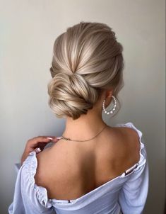 a woman with blonde hair wearing a white dress and pearl earrings, looking off to the side