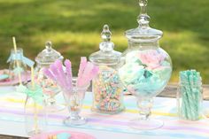 there are many candy in glass vases on the table