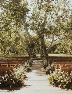 an outdoor ceremony setup with wooden benches and flowers