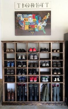 a wooden shelf filled with lots of pairs of shoes next to a wall mounted sign